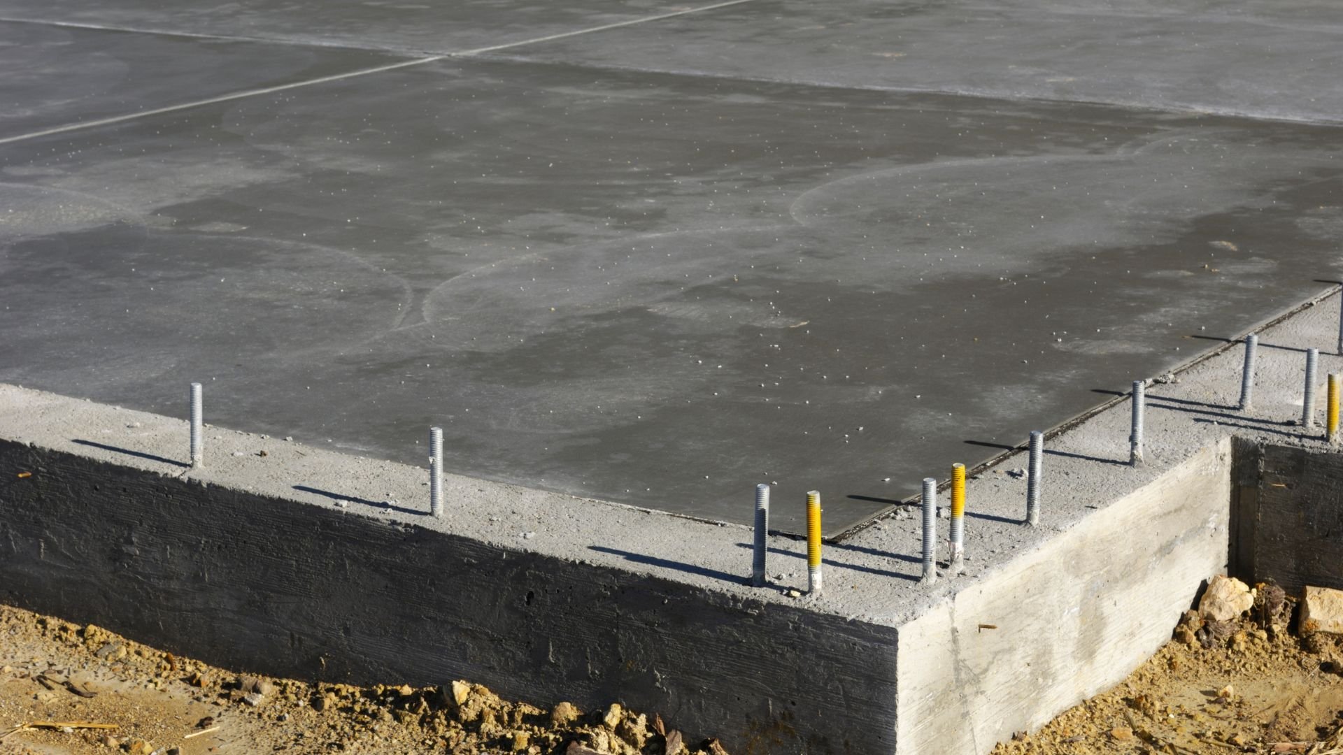 Concrete foundation with metal anchor bolts and waterproofing layer