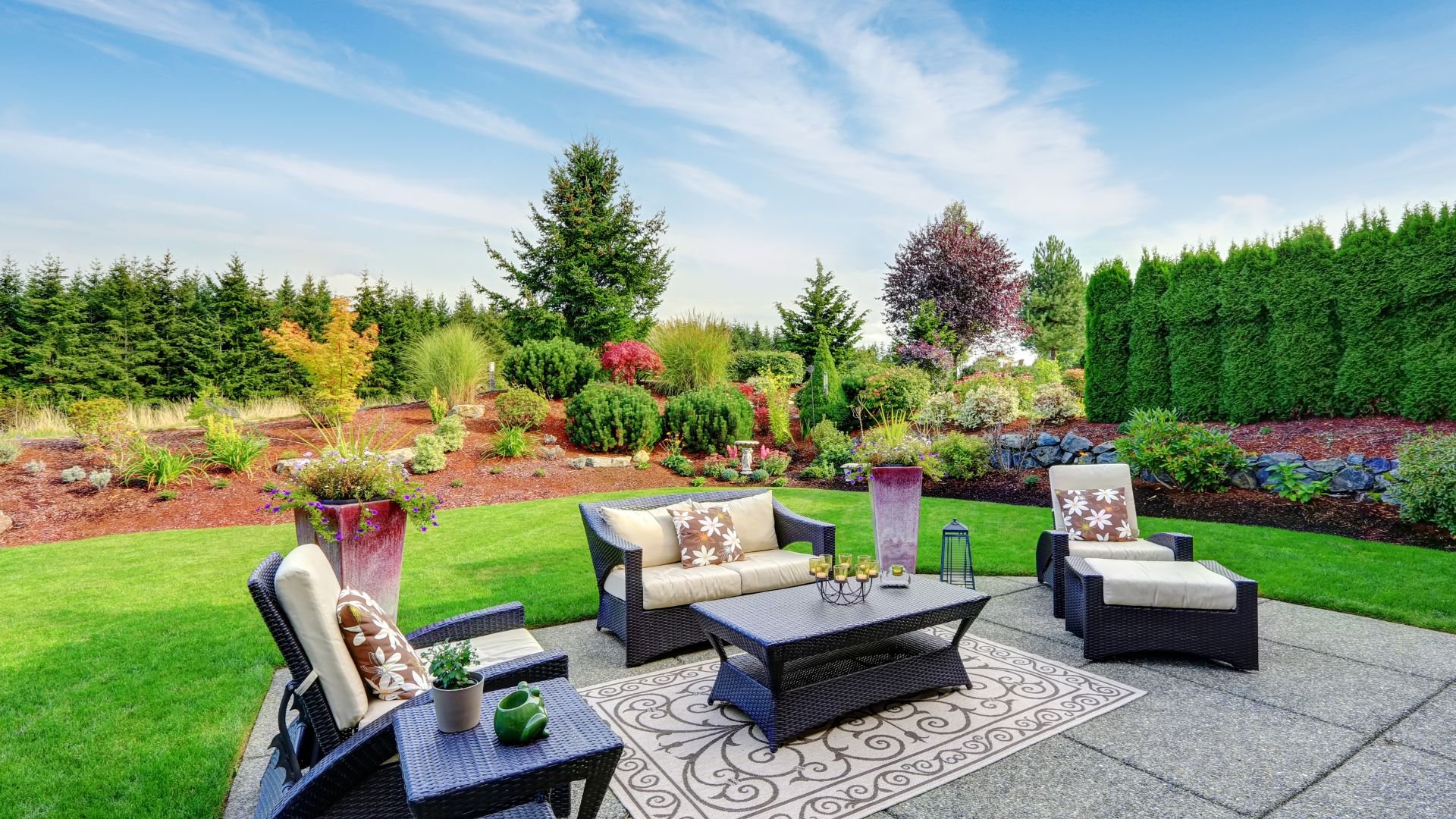Luxurious backyard patio with outdoor furniture and well-manicured landscaping