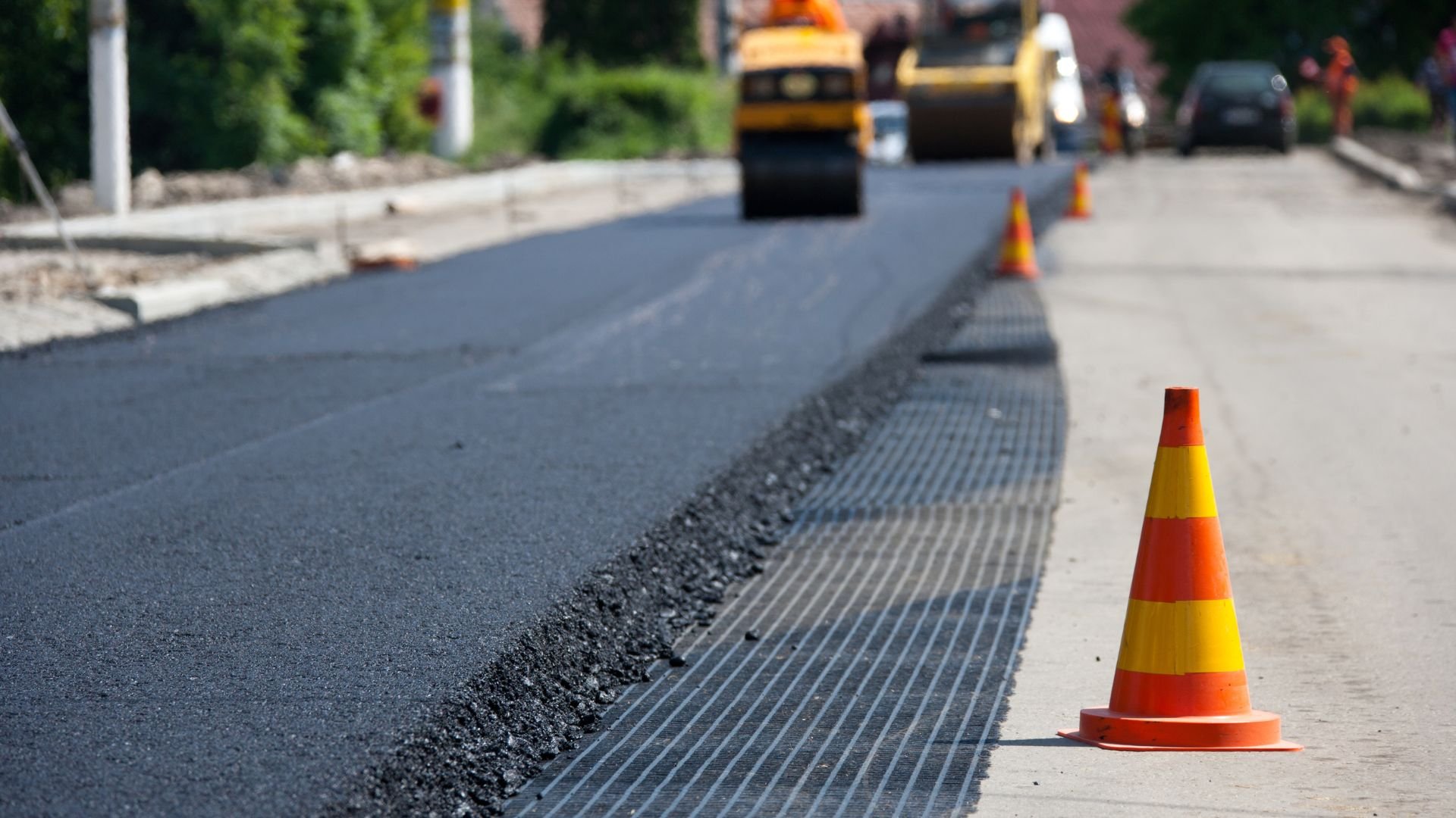 Road paving with roller and safety cone on urban street construction site